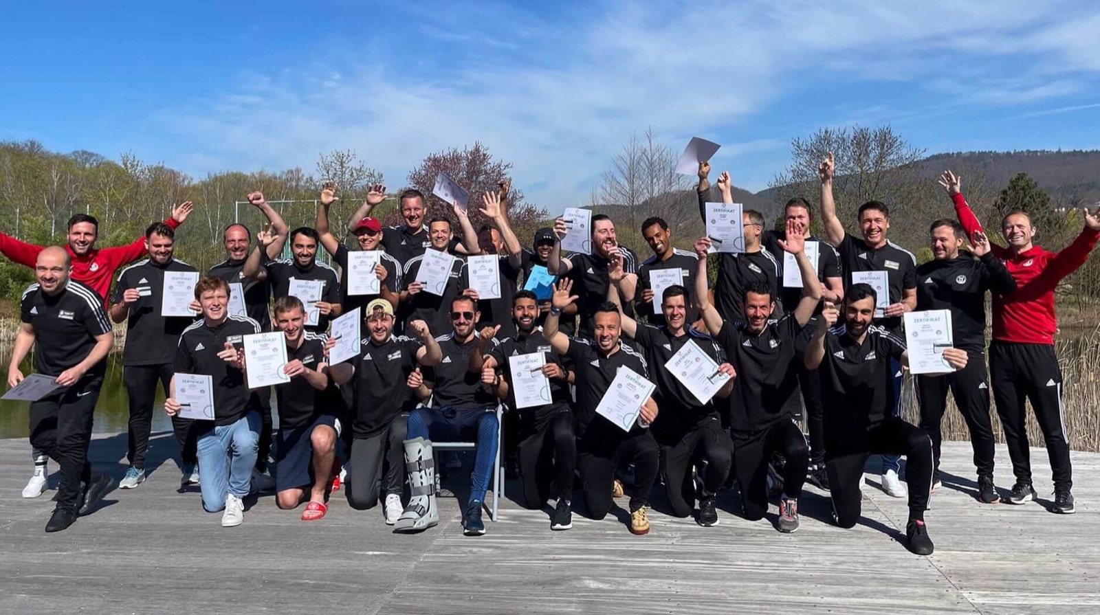 Course graduates holding their certificates at the end of an in-person course.